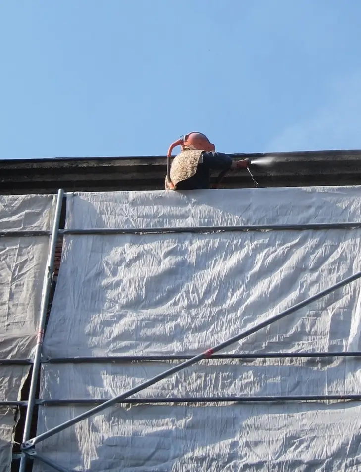 Photo d'une personne qui nettoie une façade sur un échaffaudage