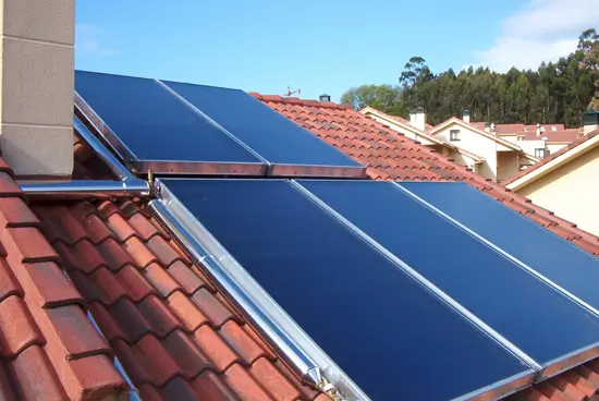 Capteurs solaires thermiques plans vitrés installés sur un toit en tuiles