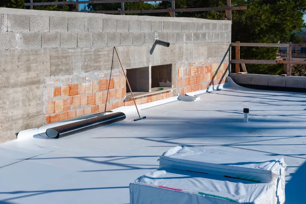 Pose d’une membrane d’étanchéité EPDM sur une toiture plate, avec relevés contre le mur de façade.